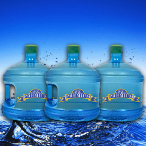 Three large blue water jugs with green caps labeled "Crystal Premium" are arranged in front of a blue water background with splashes, showcasing the refreshing quality of Spring Water. Perfect for your Bottle Plan, each container holds 3 Gallon Glass capacity for pure hydration.