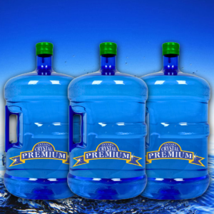 Three large blue water jugs with green caps, labeled "Crystal Premium," are placed in front of a blue gradient background with water at the bottom, evoking the refreshing purity of spring. Perfect for any bottle plan, these containers offer convenience and style, and are available in a sturdy 3 gallon glass option.