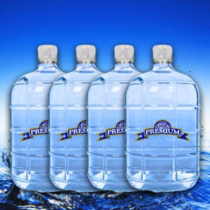 Four large bottles of Crystal Premium purified water stand side by side against a blue background, with water splashing at the bottom—a perfect visual for your next bottle plan or when you need a refreshing 3 gallon glass option.